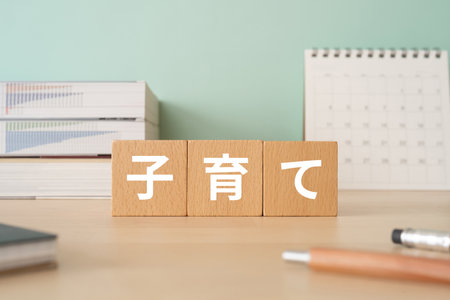 Wooden blocks with "kosodate" text of concept, pens, notebooks, and books.の写真素材