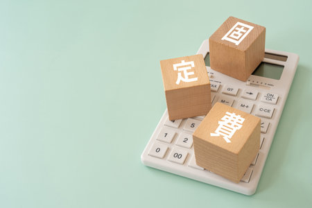 Wooden blocks with "koteihi" text of concept and a calculator.の写真素材