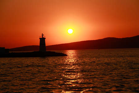 Silhouette of a lighthouse. Lighthouse silhouetted against a sunset.の写真素材