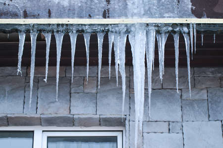 Large icicles on the roof of the building. Fines for snow and ice on roofs.の写真素材