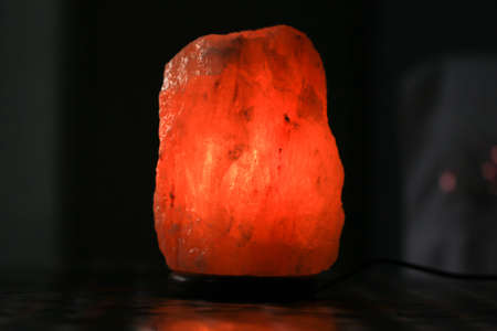 Lamp placed inside of salt stone on dark background. Popular crystal rock nightlight giving mood lighting.の写真素材