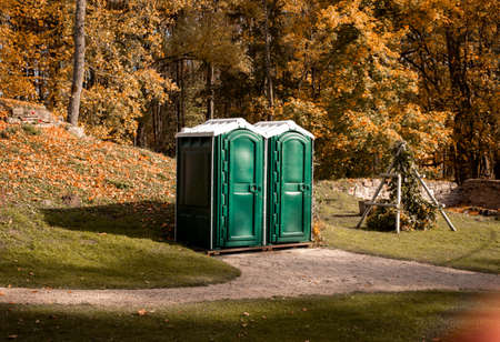 Two portable green toilet cabins in park at dry sunny autumn dayの写真素材