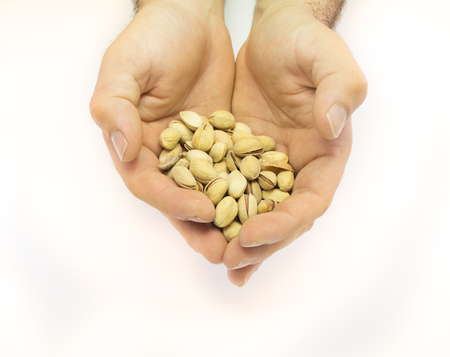 hand holding pistachio nut isolated on white backgroundの写真素材