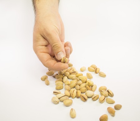 hand holding pistachio nut isolated on white backgroundの写真素材