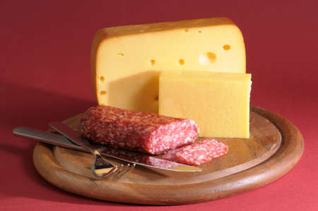 Cheese and salami still life against red backgroundの写真素材