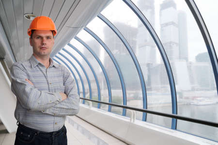 Architect in hard-hat against modern buildingの写真素材