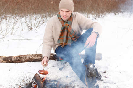 Man roasts a sausage at firecampの写真素材