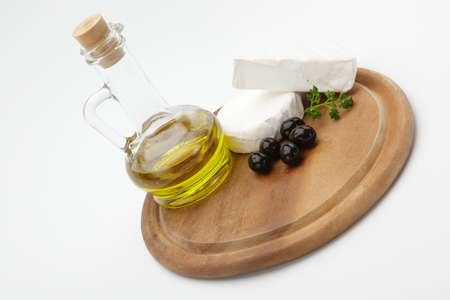 Delicious cheese, olives and olive oil on a wooden cutting boardの写真素材