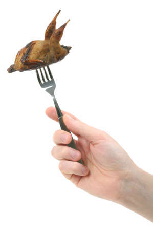 Hand holding fork with roasted quail の写真素材