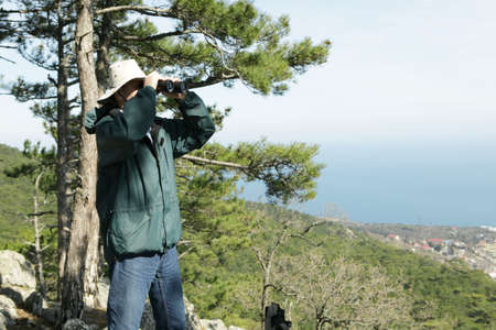 Hiker with binoculars in mountainsの写真素材
