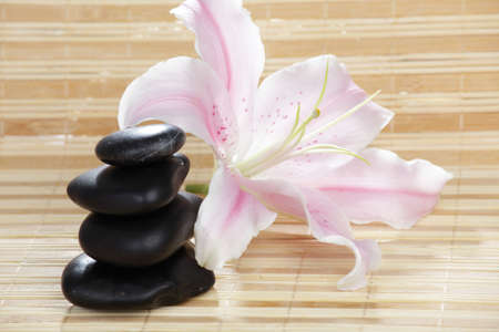 Lily flower and stack of pebbles on a straw matの写真素材