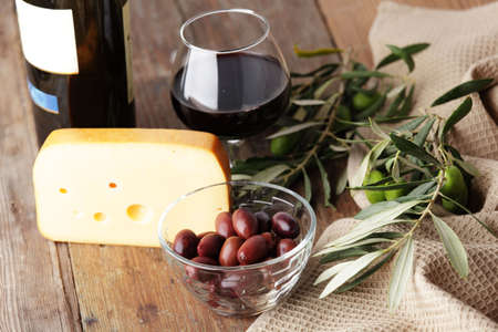 Yellow cheese, olives, and red wineの写真素材