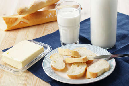 Breakfast with fresh baguette, butter, and milkの写真素材