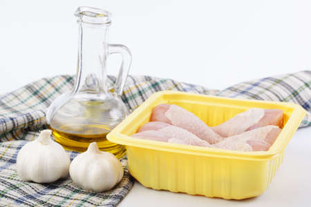 Pack of raw chicken legs, garlic and olive oilの写真素材