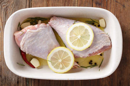 Raw turkey legs in white casserole with lemon and rosemaryの写真素材