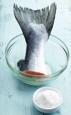 Raw salmon tail in a glass bowl on a rustic tableの写真素材
