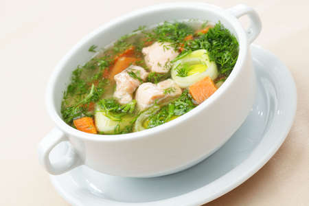 Soup with salmon and vegetables in a white bowlの写真素材