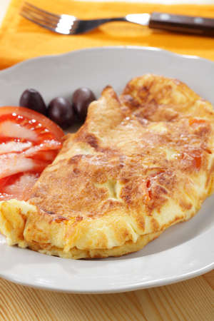 Omelet with tomato and olives on white plate