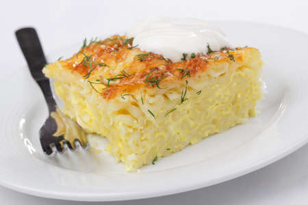 Gratin with pasta, beaten eggs, and cheese, plated with dill and sour creamの写真素材
