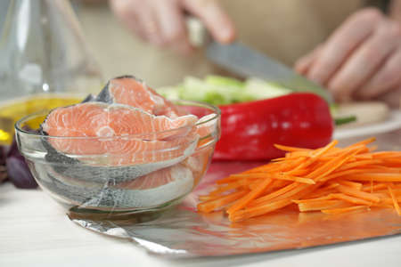 Cutting vegetables for cooking baked salmonの写真素材