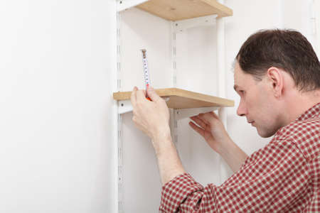 Man installing wooden shelves on bracketsの写真素材