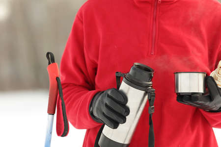 Cross-country skier pouring hot drink from bottle to a cupの写真素材