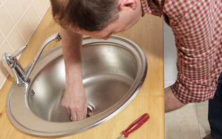 Man installing a drain for a kitchen sinkの写真素材