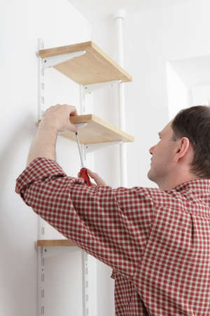 Man installing wooden shelves on bracketsの写真素材