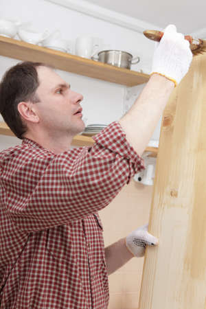 Man varnishing wood shelves for kitchen renovationの写真素材