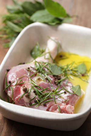 Goose leg with spices and olive oil in white casserole before cookingの写真素材