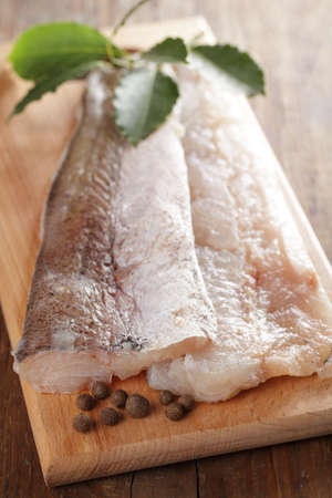 Raw fillet of hake on the cutting board with spices