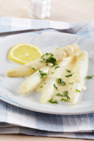 White asparagus under cheese sauce with parsley and lemonの写真素材