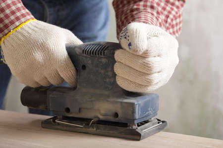 Carpenter sanding the wooden plank using power toolの写真素材