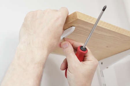 Man installing wooden shelves on bracketsの写真素材