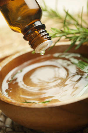 Drop of aromatic oil above the wooden bowl の写真素材