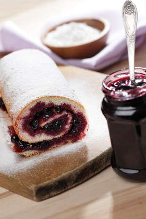 Swiss roll with black currant jam under powdered sugarの写真素材