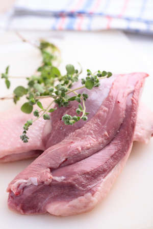 Raw goose breast with marjoram on a cutting boardの写真素材