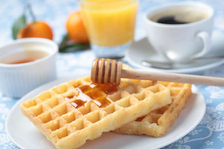 Breakfast with Belgian waffles, honey, orange juice and coffee