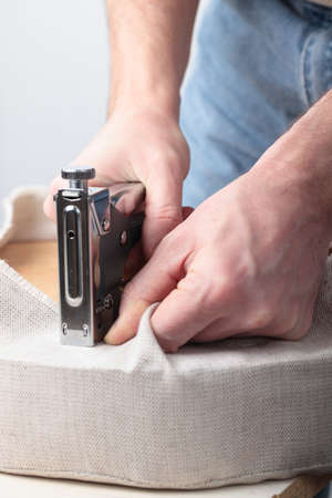 Man upholstering a round stool seatの写真素材