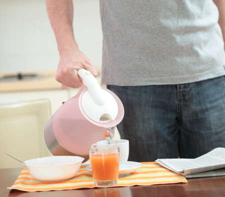 Man pouring water into a cup for his breakfastの写真素材