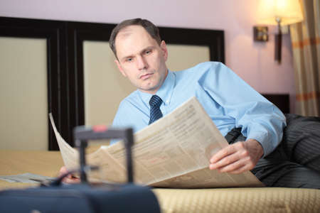 Businessman reading newspaper in a hotel roomの写真素材