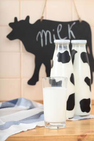 A glass and two bottles of milkの写真素材