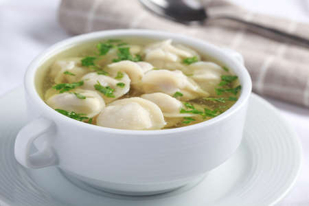 Pelmeni with chicken broth in white bowl closeupの写真素材