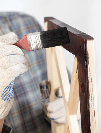 Man varnishing a wooden part of furniture using paintbrushの写真素材