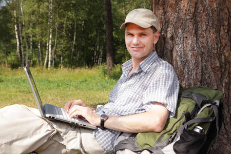 Man with laptop under a tree