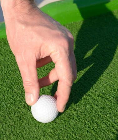 Man setting up a minigolf ball on a golf courseの写真素材