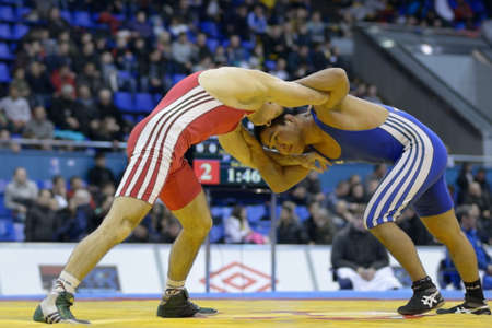 Kiev, Ukraine - February 16, 2013: Match between Ool Mortuy Enmengi, Russia, blue and Dmitriy Sivakov, Belarus during XIX International freestyle wrestling and female wrestling tournament in Kiev, Ukraine on February 16, 2013のeditorial素材