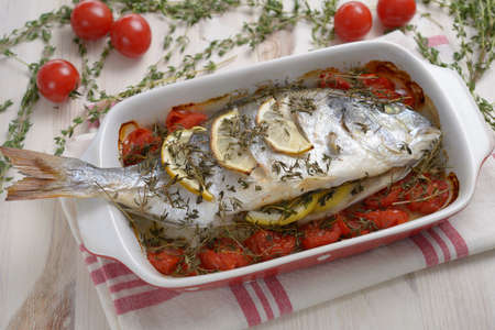 Baked gilt head sea bream with lemon, thyme, and cherry tomatoesの写真素材