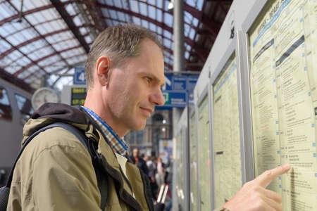 Antwerpen, Belgium - June 23, 2013  Passenger search the train in the timetable on the central train...