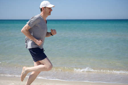 Barefoot man jogging on a beachの写真素材